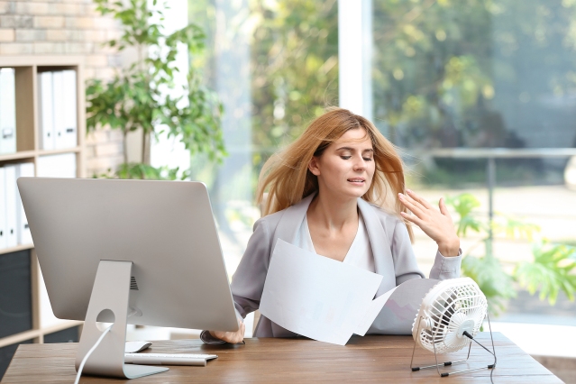 Businesswoman Suffering From Heat In Front Of Small Fan At Workp